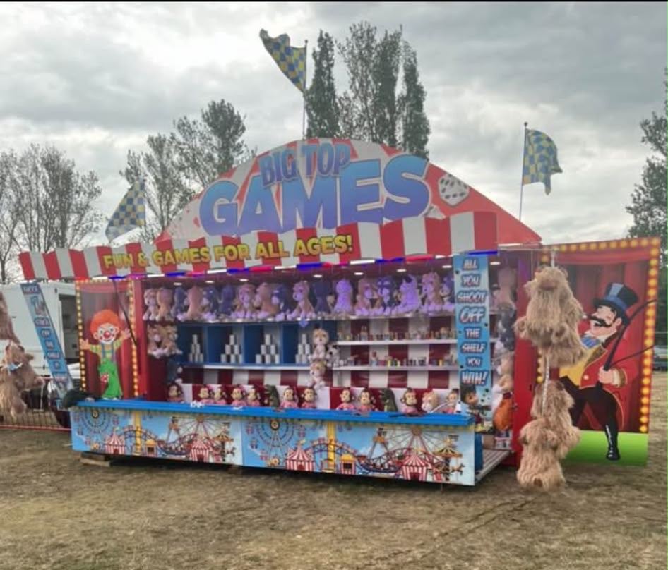 A traditional 'Big Top Games' fairground stall with prizes on display