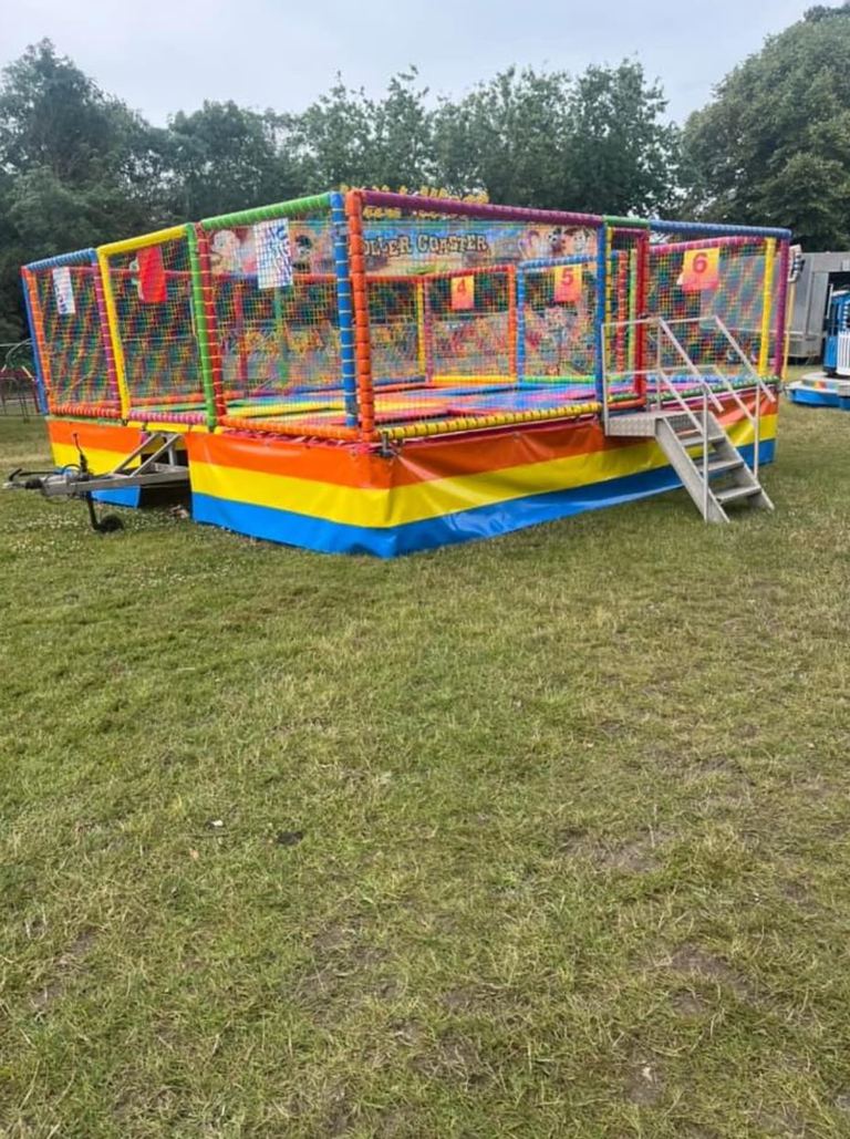 A six-bay trailer-mounted trampoline unit with rainbow safety netting