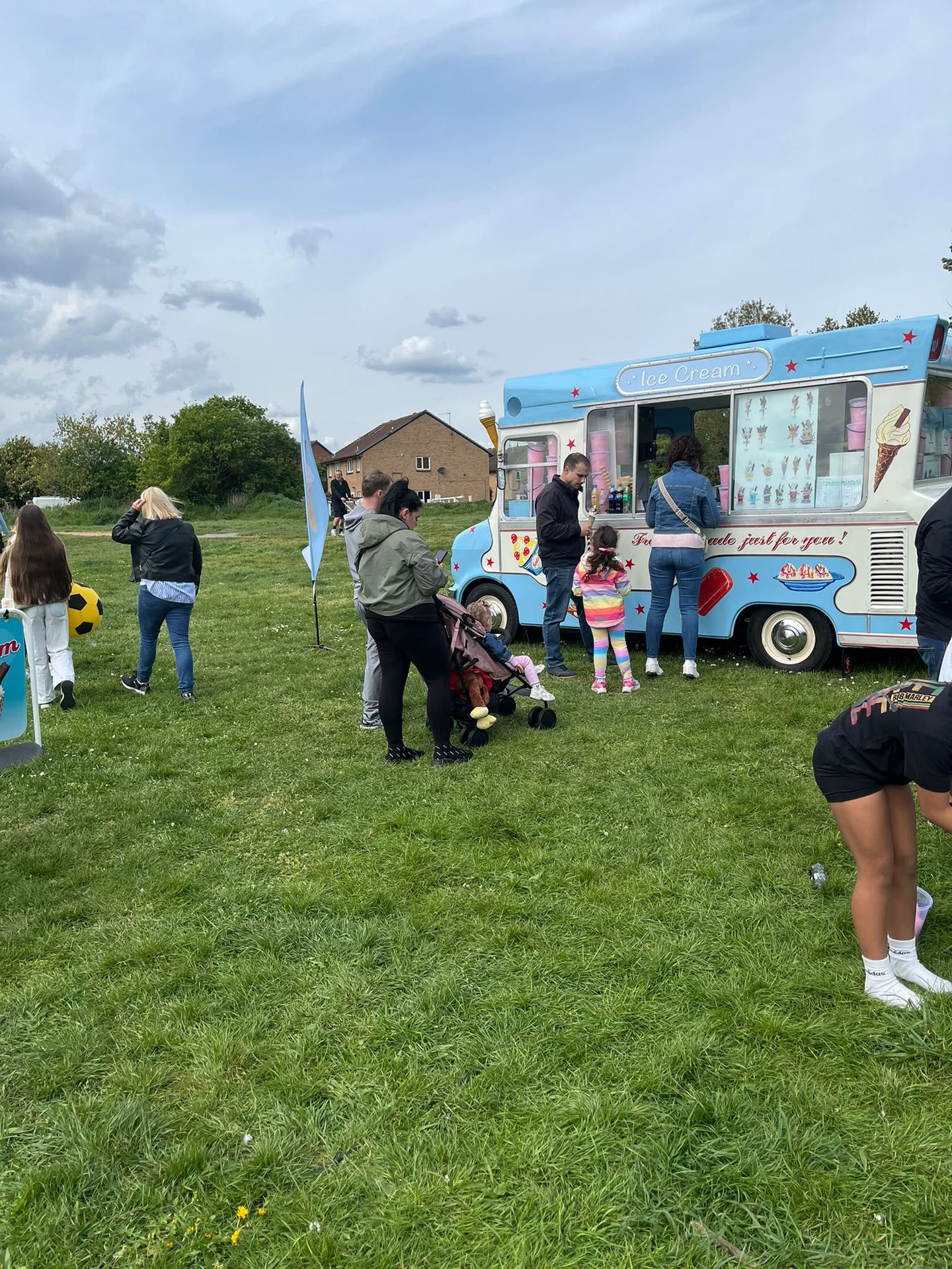A traditional blue and white ice cream van serving customers at an outdoor event