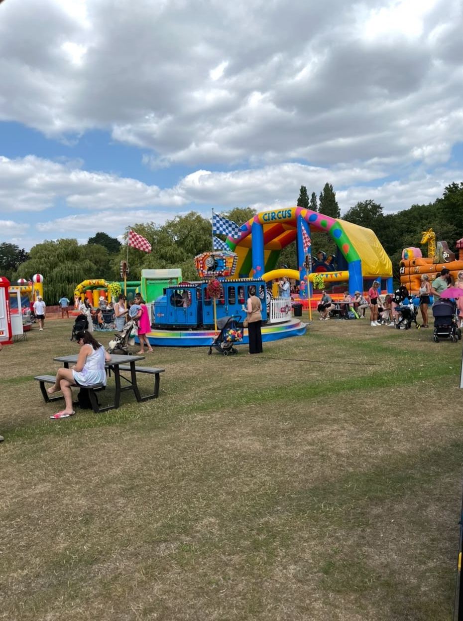 Families at picnic tables beside a circus inflatable and Toy Town train ride