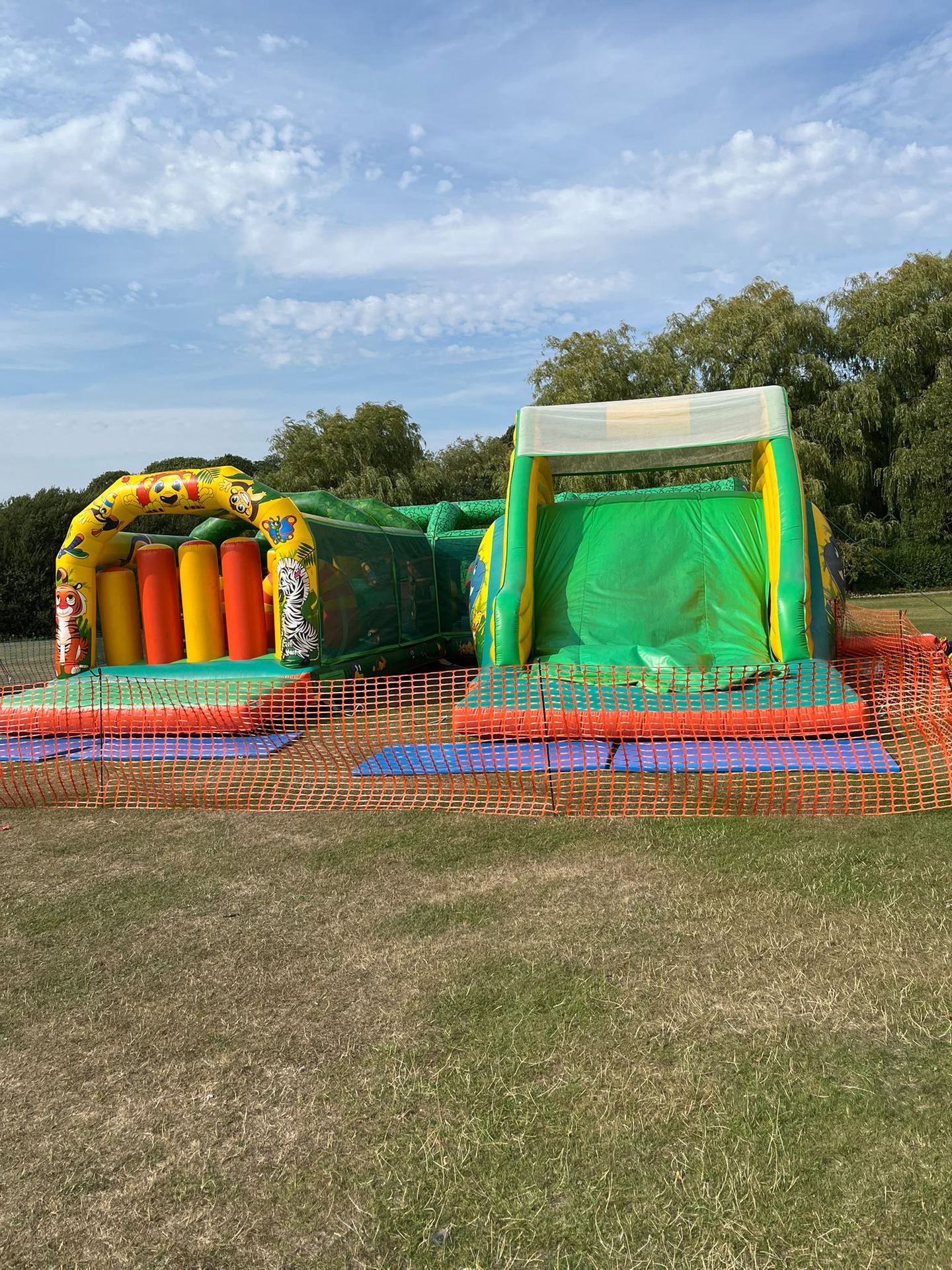 A jungle-themed inflatable obstacle course against a blue sky