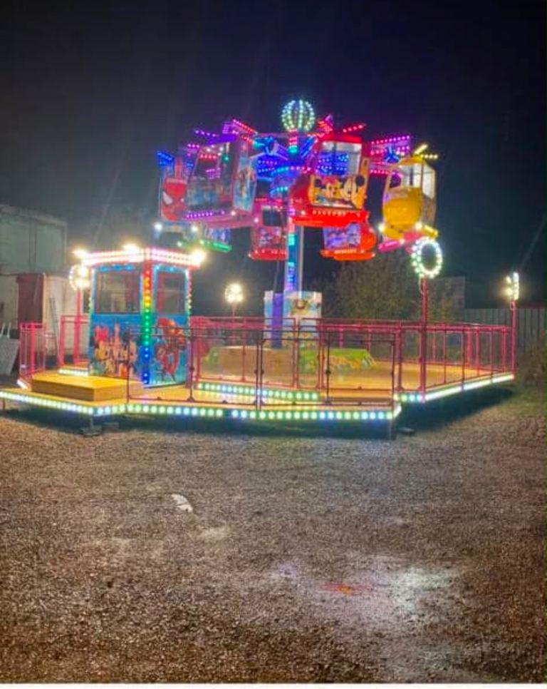 A kids' helicopter ride lit up at night with helicopter and character cars
