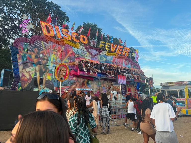 The Disco Fever Miami thrill ride with riders along an illuminated arm