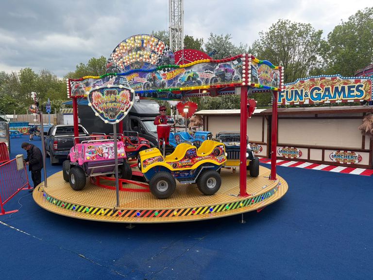 A kids' Monster Trucks ride with themed monster truck cars on a lit turntable