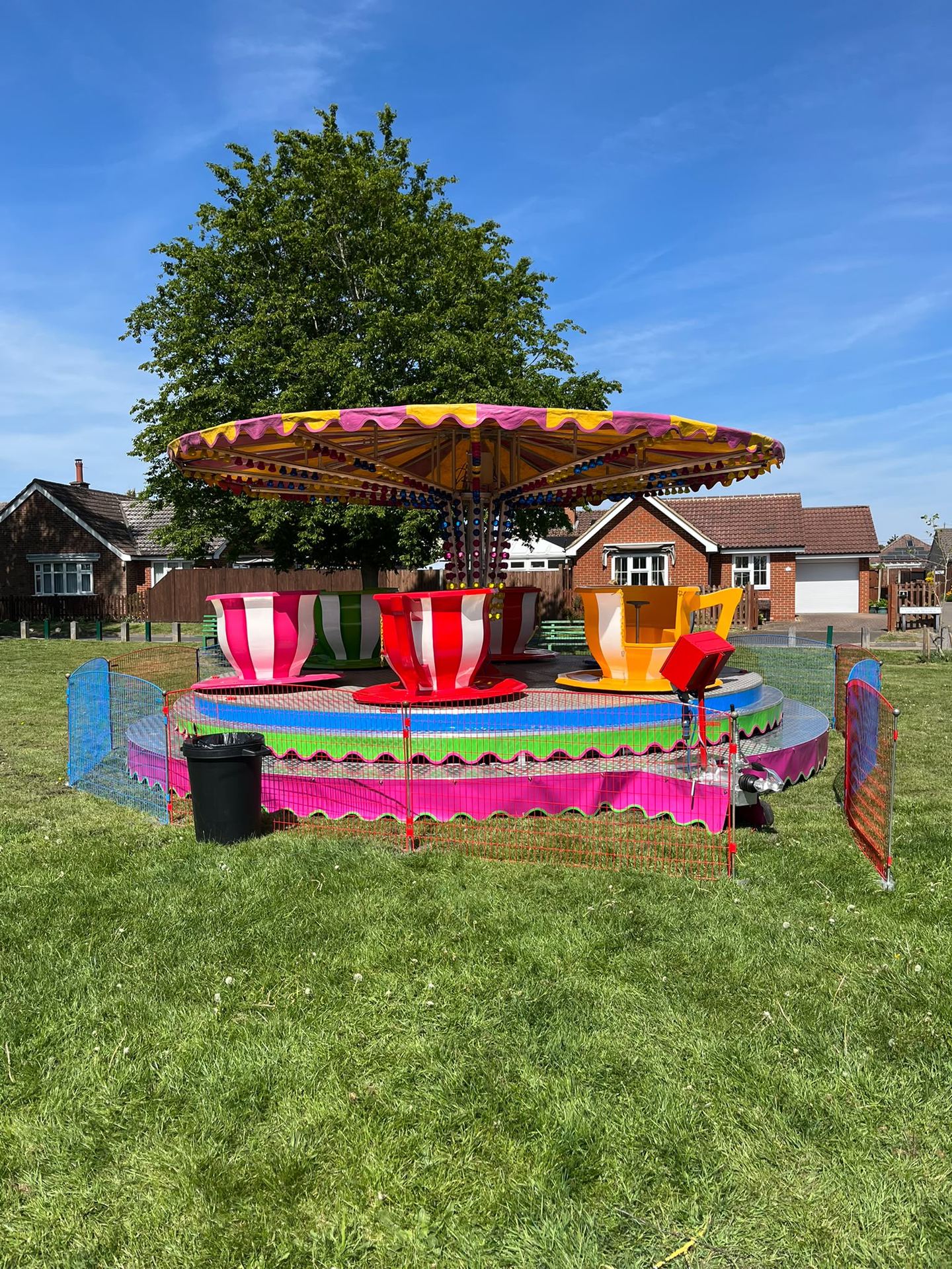 A colourful teacups spinning ride set up in a garden